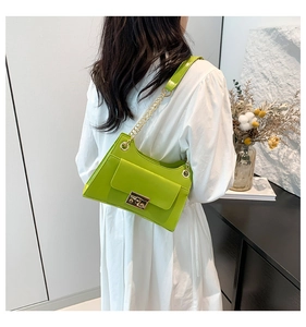 Detail of bright lime green shoulder bag with golden chain strap on a white dress model