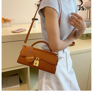 Brown rectangular shoulder bag with wavy edge flap and gold metal clasp shown on model
