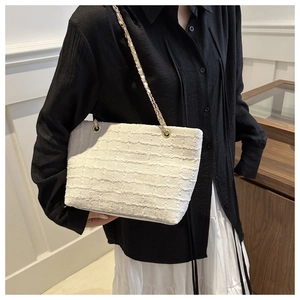 Détail du sac cabas blanc tissé avec texture à franges et élégante chaîne dorée