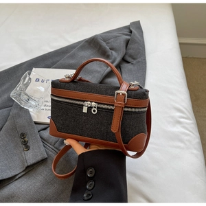 Close-up of denim vanity case bag with brown leather trim and silver metal hardware