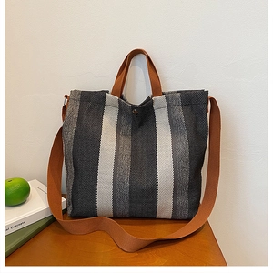 Détail du sac cabas en toile rayée avec anses brunes et bouton pression métallique
