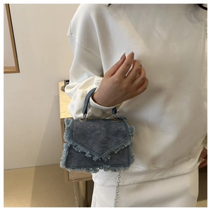 Detail of dark blue denim mini bag with fringed edges and silver chain strap