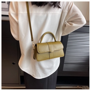 Olive green leather crossbody bag with gold hardware shown on a model in a white shirt