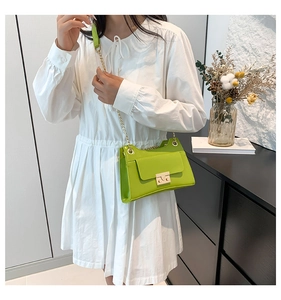 Detail of neon green square shoulder bag with gold chain strap on white dress