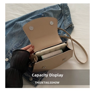 Detail showing the magnetic closure and interior capacity of the beige crossbody bag