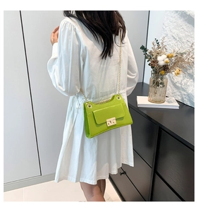 Detailed view of neon green crossbody bag with gold chain strap worn by a model