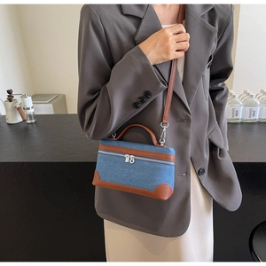 Detail of a denim patchwork mini square bag with brown leather trim and silver zipper