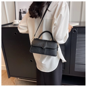 Detail showing matte black leather texture and triangular buckle on elegant handbag