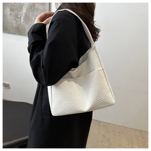Detailed view of white woven shoulder bag texture on model wearing black coat