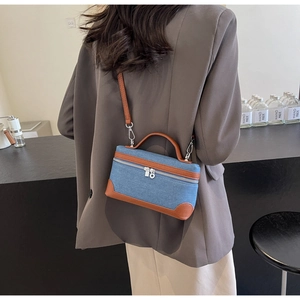 Detailed shot of a blue denim patchwork handbag with brown leather straps for women