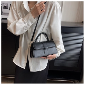 Model view of black minimalist matte leather crossbody bag with pointed flap and slim strap
