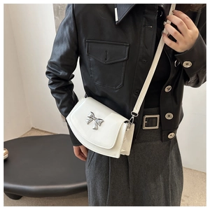 Detail of white mini crossbody bag with glossy finish and silver bow metal buckle