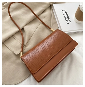 Borsa a tracolla marrone con stampa coccodrillo abbinata a un blazer color kaki