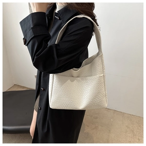 Detail of cream woven tote bag showing the textured surface and wide shoulder strap
