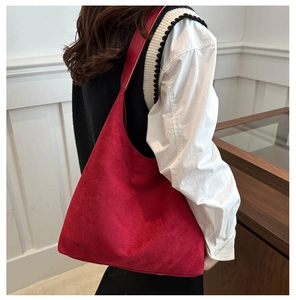 Détail d'un grand cabas en daim rouge porté à l'épaule dans un intérieur épuré