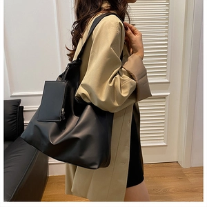 Minimalist black PU leather tote bag with small pouch shown as shoulder wear