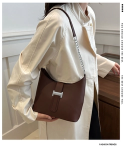 Close-up of dark brown leather shoulder bag with silver H-buckle and metal chain strap
