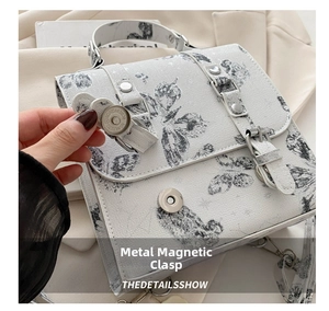 Close-up of metal magnetic buckle and butterfly print on gray fabric shoulder bag