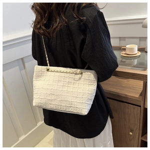 Détail du sac cabas en tweed blanc avec chaîne dorée porté par un mannequin