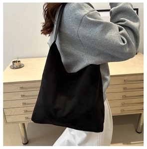Détail d'un grand sac cabas en daim noir à texture douce, porté en sac à bandoulière