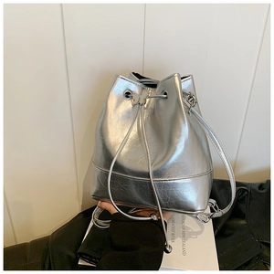 Detail of silver metallic bucket bag featuring vintage texture and butterfly drawstring