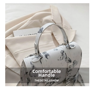 Detailed view of white textured handbag featuring gray butterfly prints and silver hardware