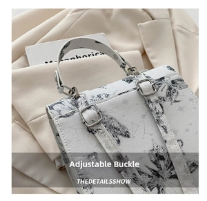 Detail of adjustable metal buckle and black floral print on white crossbody bag