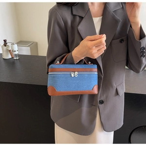 Detail of denim and brown leather patchwork handbag with dual metal zippers