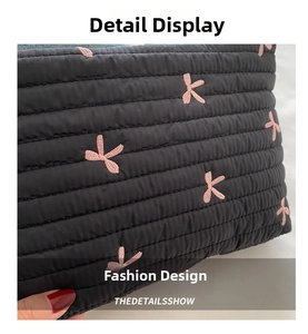Close-up of black quilted bag featuring pink flower embroidery and textured stitching