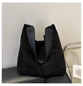 Détail de la texture en daim noir du sac fourre-tout avec anse en cuir sur une chaise