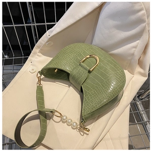 Detail of green faux crocodile saddle bag with gold D-buckle and pearl chain strap