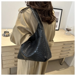 Detail view of the black woven texture and broad shoulder strap on a chic PU hobo bag