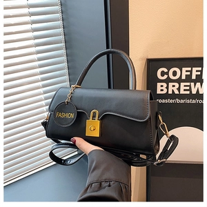 Detail of black faux leather shoulder bag with gold clasp and Fashion brand tag
