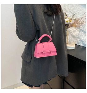 Détail d'un mini sac bandoulière rose vif avec texture cuir grainé et chaîne argentée