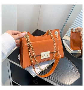 Side view of caramel orange chain shoulder bag with gold clasp and mirror reflection