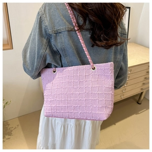 Sac fourre-tout en tweed rose avec chaîne dorée porté par un mannequin au style chic
