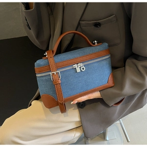 Close-up of denim patchwork handbag with brown leather trim and silver zipper detail