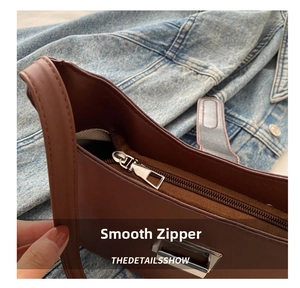 Close-up of smooth silver metal zipper on a premium brown leather shoulder bag