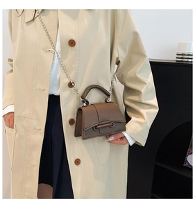 Détail d'un mini sac en cuir marron motif litchi avec une bandoulière chaîne argent