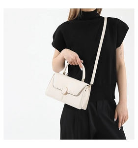 Detail of cream white textured crossbody bag with gold-tone oval twist lock and top handle