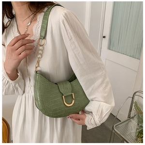 Green crocodile pattern moon bag with pearl strap and gold buckle on white dress