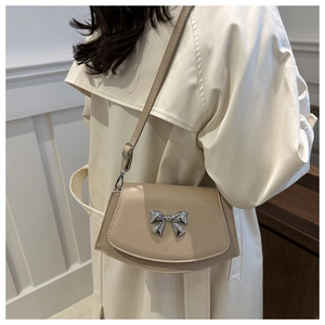 Detail of beige saddle bag with silver mirror bow and adjustable shoulder strap