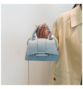 Détail du sac en cuir grainé bleu clair avec bandoulière chaîne et poignée haute