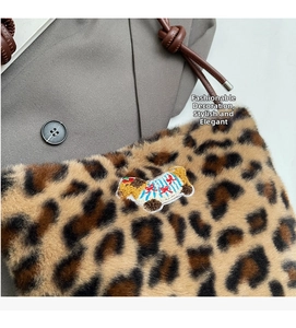 Close-up of leopard print plush handbag with cartoon embroidery and leather strap