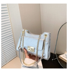 Close-up of textured silver square bag with chunky gold chain and metal clasp detail