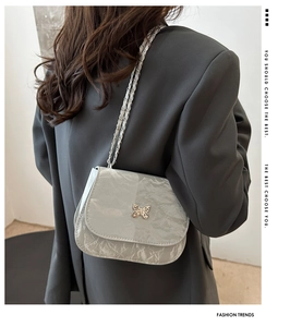 Detail of silver saddle bag with pleated texture and exquisite butterfly metal buckle