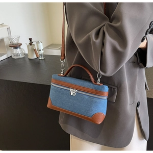 Detail of denim and brown leather patchwork crossbody bag with dual zipper closure