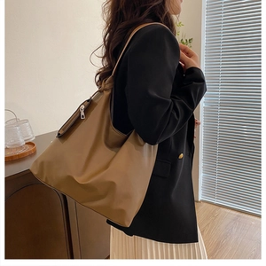 Brown soft leather tote bag worn by model in a minimalist cozy indoor setting