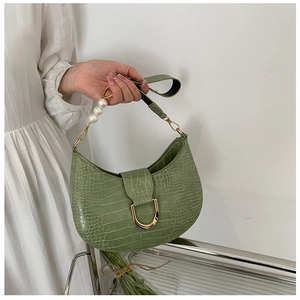 Close-up of light green crocodile embossed crescent bag with gold buckle and pearl handle