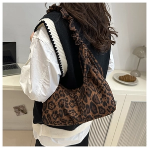 Detail of leopard print tote bag featuring ruffled shoulder strap and crescent shape